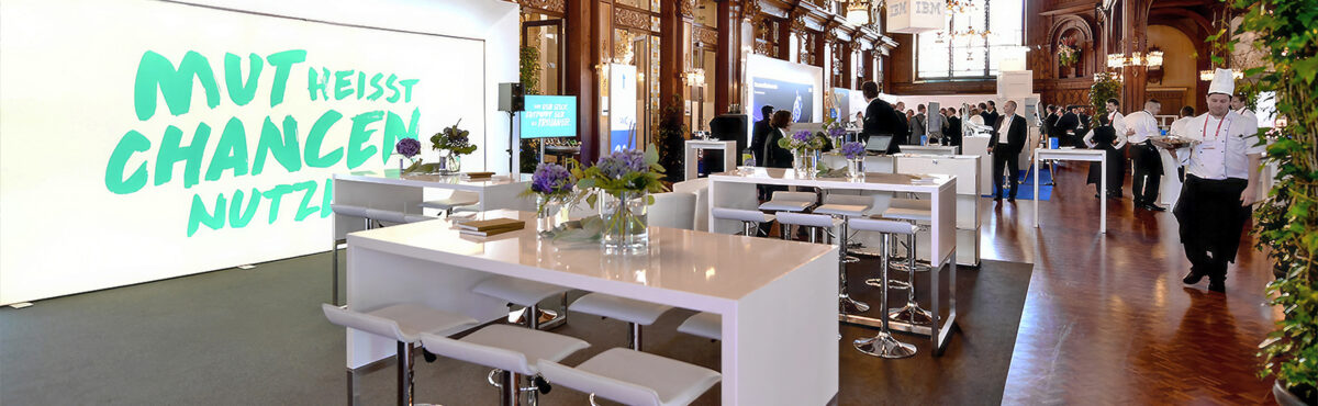 weisse stehtische mit barhockern auf einem messestand mit beleuchteter Messwand und Teppich