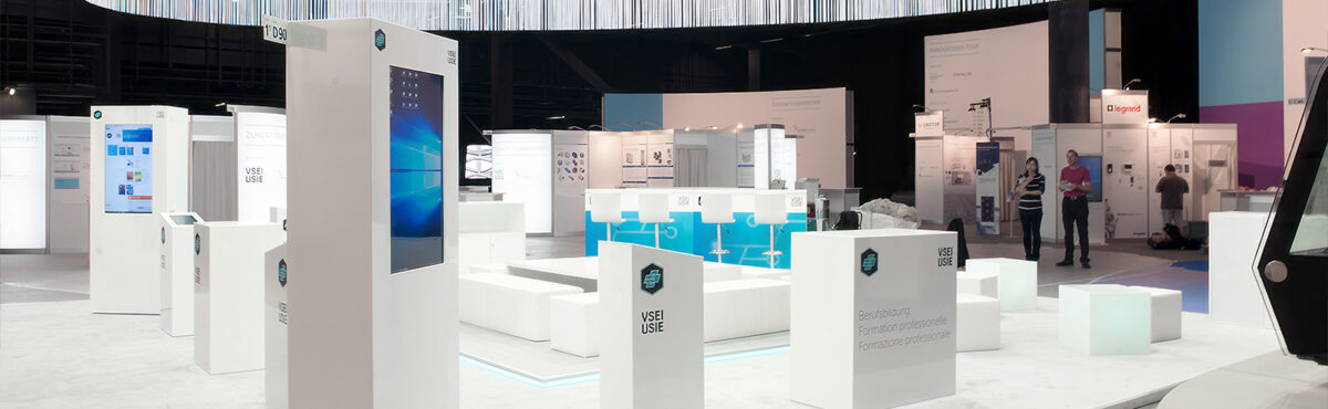 kundenstopper tv screen auf einem messestand mit weissem mobiliar