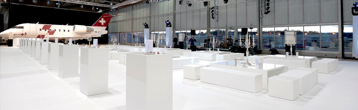 event moebel mit saeulen stehtischen und lounge in weiss in einem hangar