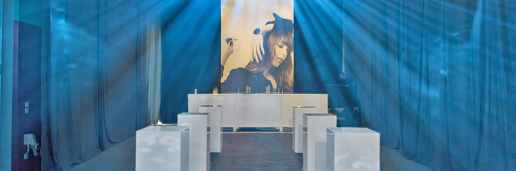 Espace bar événementiel exclusif avec comptoirs blancs et tables à colonnes illuminées en bleu