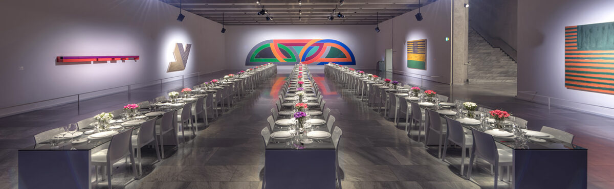 eventbankett mit langen glastischen und weissen bankettstuehlen