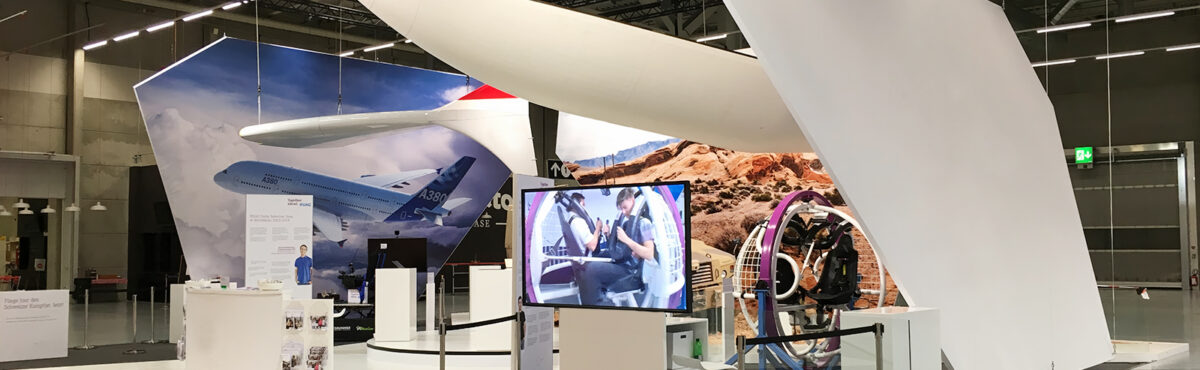 grande schermo TV su uno stand fieristico con mobili bianchi a noleggio