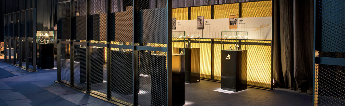 exklusiver messestand mit beleuchteten glasvitrinen und firmen logo