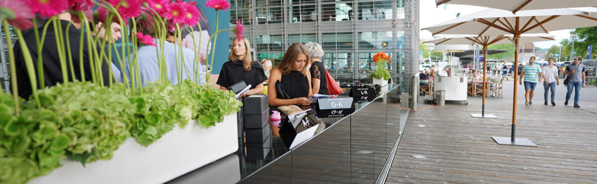 schwarze lange outdoor bartheke mit blumendeko und sonnenschirmen