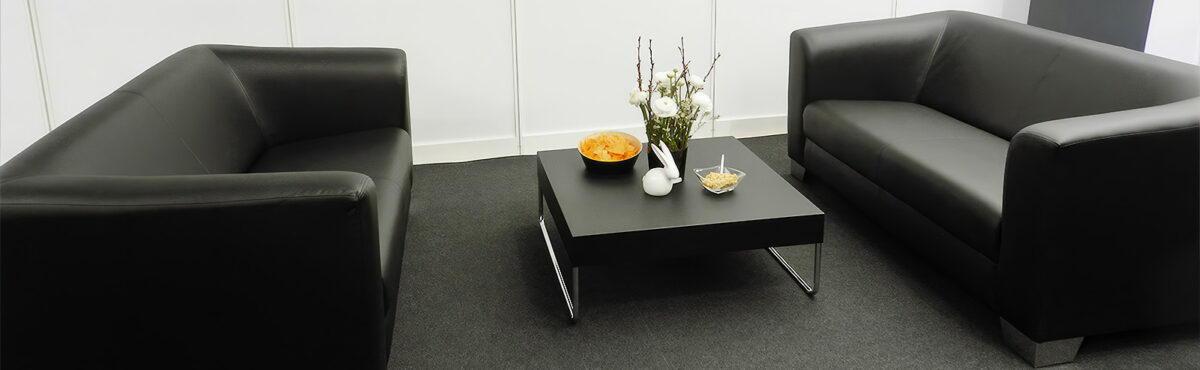 messe lounge setup mit 2 schwarzen sofas und einem beistelltisch