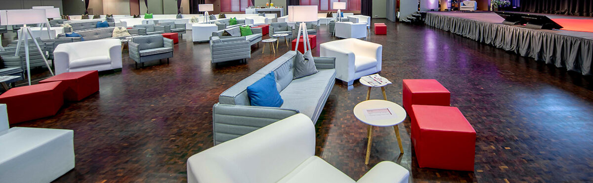 seminar lounge mit beistelltischen in weiss holz in einer eventlocation mit buehne
