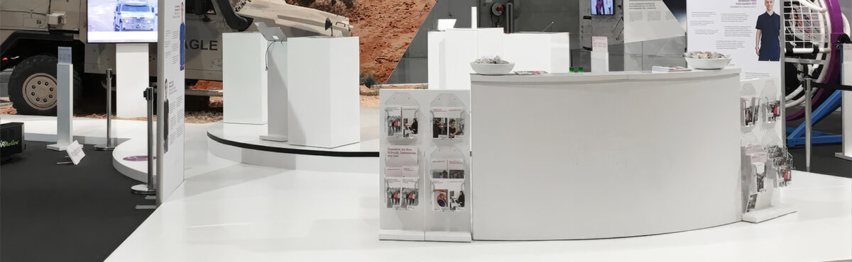 moderne prospektstaender in weiss an einer messe mit bartheke und tv screen