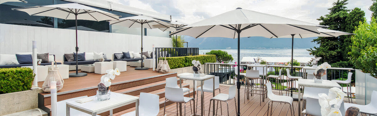 sonnenschirme in weiss und mietmoebel auf einer terrasse am see sonnenschirme in weiss und mietmoebel auf einer terrasse am see